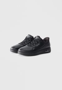 Black athletic shoes featuring smooth synthetic material, lace-up design, perforated accents, and visible air cushioning in the sole.