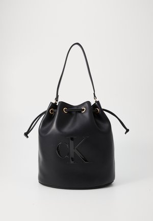 Sac seau en cuir noir avec fermeture à cordon, bandoulière simple et logo CK embossé sur le devant.