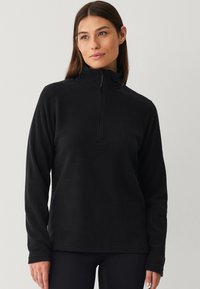 Zwarte fleece pullover met een hoge kraag en een kwart-rits voorkant. Lange mouwen met een zachte textuur en een ontspannen pasvorm. Eenvoudig en minimalistisch ontwerp.