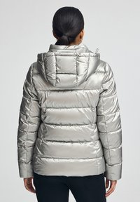 Silverfärgad vadderad jacka med huva, med vertikal sömnad, en slät yta och en lätt glansig finish.