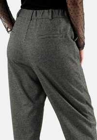 Grijze geruite broek met een relaxte pasvorm, elastische tailleband en zijzakken, met een textuuroverwerking en subtiele patroon details.