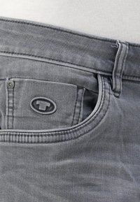 Szare jeansy z denimu z przednią kieszenią ozdobioną naszywką z logo, solidnym paskiem w talii i widocznymi detalami przeszyć.