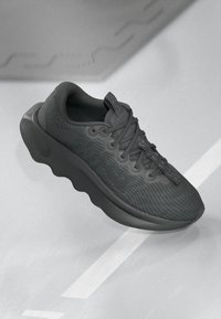 Nike atletska cipela u čvrstoj crnoj boji. Mrežasti gornji dio s suptilnim teksturalnim uzorcima, okrugli vrh, tradicionalni sistem vezivanja, podstavljeni đon.