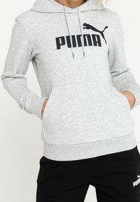 Hoodie gris en tissu en mélange de coton, avec une poche kangourou, un capuchon à cordon ajustable et un logo Puma noir sur le devant.