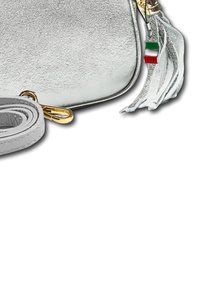 Zilveren faux suede schoudertas met gouden hardware, franjes detail en een kleine driekleurige hanger. Inclusief verstelbare schouderriem.