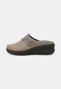 Zoccolo beige con slip-on, dotato di un motivo geometrico testurizzato, parte superiore in morbido tessuto e suola in gomma nera per trazione e supporto.