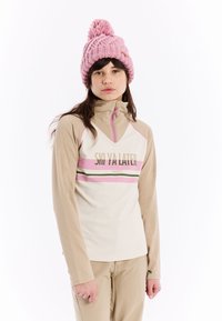 Crème langemouwen top met beige accenten en een roze horizontale streep met tekst. Een roze gebreide beanie met een pompon.