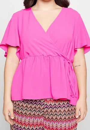 Top avvolgente rosa con maniche corte, caratterizzato da un dettaglio in vita arricciato e un design a V, abbinato a pantaloni con fantasia.