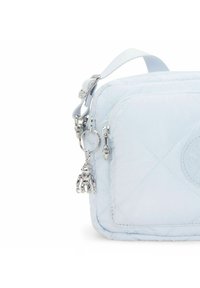 Borsa trapuntata blu chiaro con superficie textured, dotata di zip argentata e dettaglio charm. Comprende una tracolla corta e regolabile.