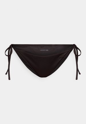 Schwarzer Lacoste-Bikini-Slip mit seitlichen Bindebändern und kleinem Krokodil-Logo auf hellem einfarbigem Hintergrund.