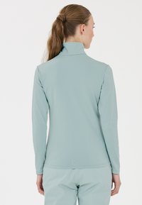 Vaaleansininen pitkähihainen paita, jossa on korkea kaulus, valmistettu sileästä ja joustavasta kankaasta. Ominaisuuksiin kuuluu minimalistinen muotoilu ja istuva leikkaus.