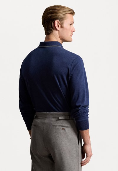 Jūras spēku tumši zilas krūšturi ar smalku apkakles detaļu, apvienotas ar gaiši pelēkiem piegriezuma biksēm, kas aprīkotas ar aizmugures kabatām un jostu cilpām.