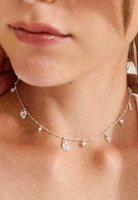 Hõbedast kett-kaelakee mitmete väikeste ripatsitega, sealhulgas süda ja dekoratiivsed pärlid, millel on peened mustrid ja õrn välimus.