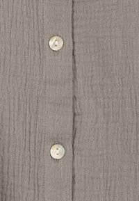 Gray textured fabric with a crinkled appearance, featuring two round, off-white buttons along the center.
