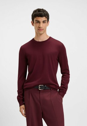 Burgundy long-sleeve sweater with a round neck, made of soft fabric. Paired with tailored burgundy trousers and a black belt with a silver buckle.