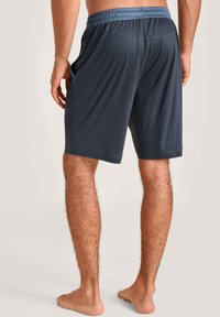 Shorts de sport gris avec une taille élastique, texture lisse et coupe ample, montrés de dos, au-dessus des genoux.