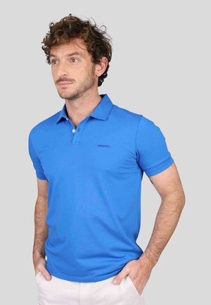 Polo bleu en tissu lisse, doté d'un col classique, de manches courtes et d'un logo discret sur la poitrine.