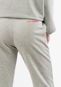 Grau Baumwoll-Sweatpants mit glatter Textur, elastischem Bund und rotem gesticktem Logo "ICE ICEBERG" auf der Rückseite.