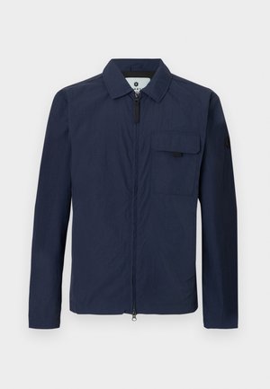 Laivastonsininen kevyt takki, jossa on kaulus, etuvetoketju ja rintatasku. Ominaisuuksina sileä pinta ja minimalistinen muotoilu.