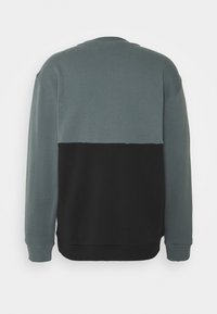 Mikina s kulatým výstřihem s barevným blokovým designem, kde je horní část světle šedá a spodní část černá, vyrobená z měkkého bavlněného materiálu.