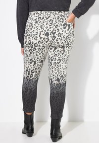 Leggings con stampa leopardata, con una sfumatura da beige chiaro a grigio scuro. Realizzati in tessuto elasticizzato, presentano tasche posteriori e un design lungo fino alla caviglia.