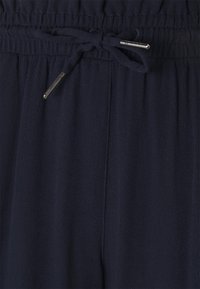 Navy blue elastic-waist pants with adjustable drawstring. Soft, textured fabric with a relaxed fit and side seam pockets.