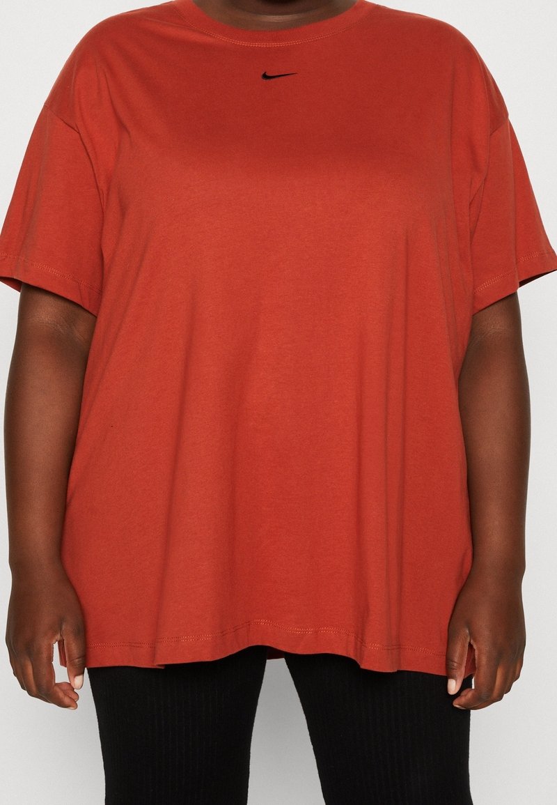 Röd bomulls-T-shirt med avslappnad passform, korta ärmar och en liten svart Nike-logga på bröstet. Slät textur med rundad halsringning.