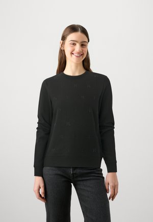 Svart hettegenser med rund hals, lange ermer og et strukturelt mønster med små bokstav 'M' aksenter over stoffet.