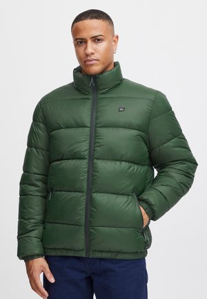 Gewatteerde groene jas met hoge kraag, voorrits en twee zijzakken. Heeft een logo op de borst en een paneelstructuur.