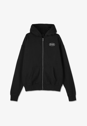 Crna zip-hoodie napravljena od mekane pamučne tkanine. Ima kengurua džep i rebraste manžete. Mali logo na grudima u bijeloj boji. Klasični dizajn i kroj.