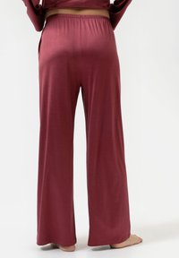 Bordeaux wijde broek met een elastische tailleband, gemaakt van zachte stof, met een gladde textuur en zijzakken.