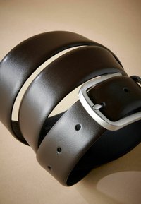 Cinturón de cuero marrón con un acabado liso, tres agujeros visibles y una hebilla de metal plateado. El diseño es clásico y angulado.