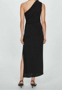 Robe noire à une épaule avec un design froncé, fente latérale et ourlet à la cheville. Confectionnée dans un tissu léger et lisse.