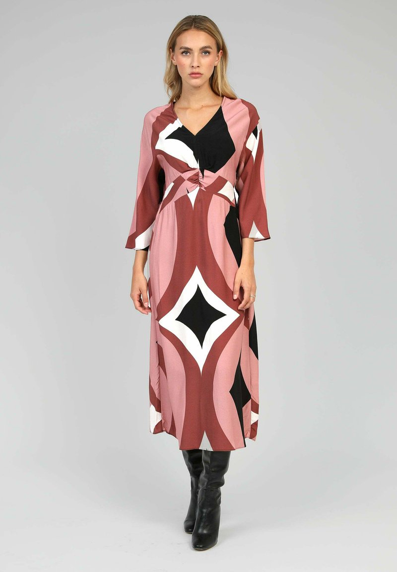Robe longue à motifs avec un décolleté en V, un détail noué à la taille et des manches trois-quarts. Les couleurs comprennent le rose, le noir et le blanc.
