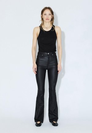 Top sans manches noir associé à un pantalon en cuir noir à taille haute et évasé. Design simple avec un matériel minimal et une texture lisse.