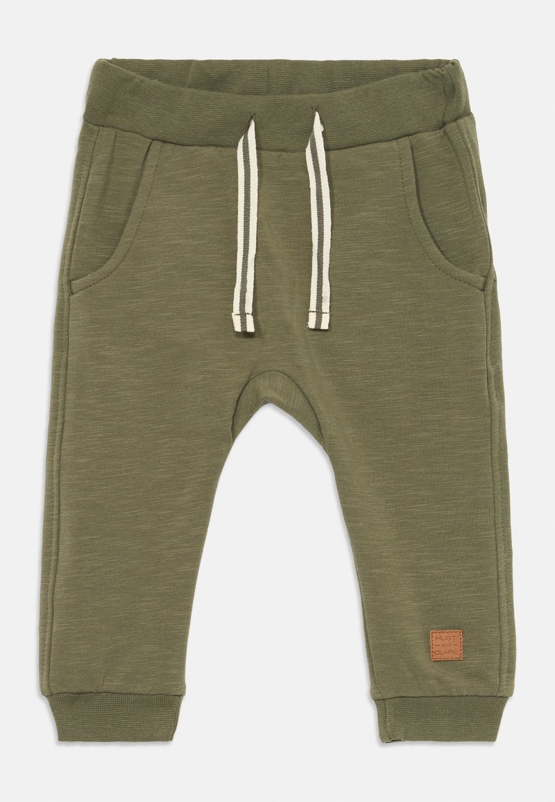 Vihreät joggers-housut, joissa on pehmeä kangas, elastinen vyötärö valkoisilla naruilla ja kaksi sivutaskua. Nahkainen merkkipainatus.