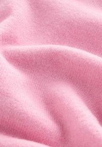 Tissu rose doux avec une texture lisse, présentant un motif en maille fine et des rainures subtiles. Le matériau semble léger et confortable.