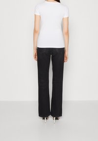 T-shirt blanc à manches courtes associé à un jean évasé noir. Le jean dispose de poches arrière et d'une finition soignée aux ourlets.