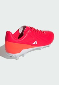 Scarpa da calcio rossa con tomaia in materiale sintetico, design texturizzato, dettagli bianchi e un tallone a contrasto. Presenta tacchetti modellati per una migliore aderenza.