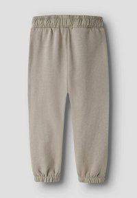Jasnobeżowe spodnie dresowe wykonane z bawełnianej mieszanki tkaniny, z elastycznym pasem i ściągaczami przy nogawkach, gładka faktura, bez widocznych wzorów.