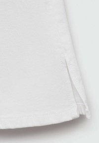 Witte katoenen shirtzoom met zijsplitten. Heeft een gladde textuur en nette stiksels langs de randen. Eenvoudig en functioneel ontwerp.