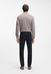 Ανοιχτό γκρι τοπ μακρυμάνικο, άνετη εφαρμογή, με ριμπ υφή. Σκούρο μπλε παντελόνι, στενή εφαρμογή, με τσέπες στο πίσω μέρος, συνδυασμένο με καφέ χαμηλά παπούτσια.