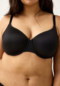 Sort bh med underwire, glat stof, justerbare stropper og bølget blondetrim langs udskæringen; formede skåle for støtte.