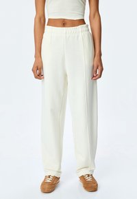 Crème-kleurige, luchtige sweatpants met een elastische tailleband en zijnaad; gemaakt van zacht katoen.