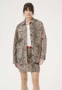 Giacca con stampa leopardata realizzata in tessuto leggero, caratterizzata da una forma squadrata, ampie tasche e un colletto, abbinata a una gonna coordinata.