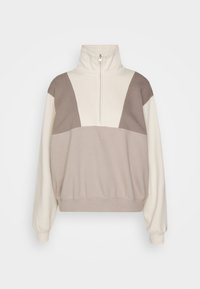 Sudadera de cuello redondo en color crema y marrón claro, con media cremallera, corte relajado y diseño panelado con diferentes texturas de tela.
