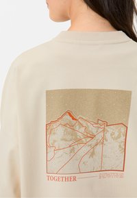 Beige Sweatshirt mit einem grafischen Bergdesign in sanftem Braun und Rot, ausgestattet mit dem Wort "TOGETHER" unterhalb der Illustration.