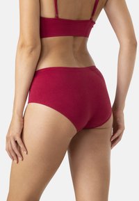 Culotte courte cramoisie en tissu lisse et extensible. Présente une taille haute et des bords sans couture pour plus de confort. Design minimaliste.