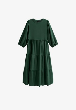 Vestito verde a balze realizzato in tessuto strutturato, con maniche lunghe a sbuffo e scollatura rotonda, dalla silhouette fluida.