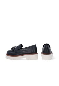 Marine leren loafers met een strikdetail, voorzien van een dikke witte plateauzool en bruine afwerking. Vloeiende textuur en afgeronde vorm.